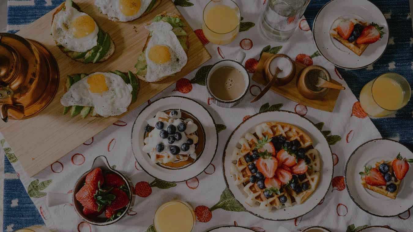 A long table of brunch dishes, fruit and drinks